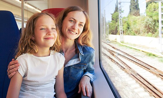 Mutter und Tochter fahren bei schönem Wetter mit dem Zug
