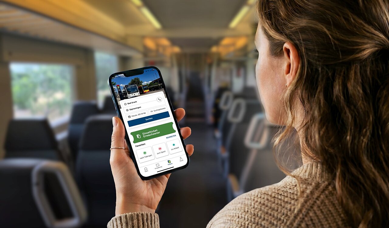 Junge Frau sitzt in Regionalbahn und schaut auf Ihr Handy mit geäffneter naldo-App