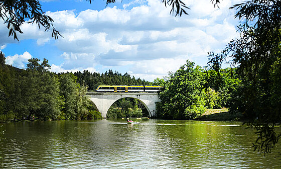 Freizeitexpress Schieferbahn fährt bei schönem Wetter über Schlichemviadukt beim Schömberg-Stausee